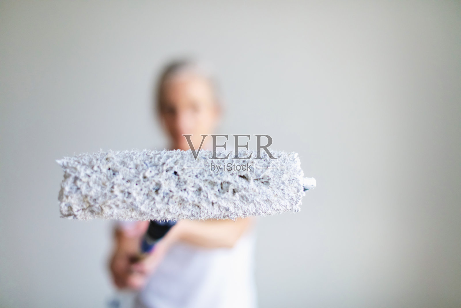 成年女性用油漆滚筒把墙壁刷成白色照片摄影图片