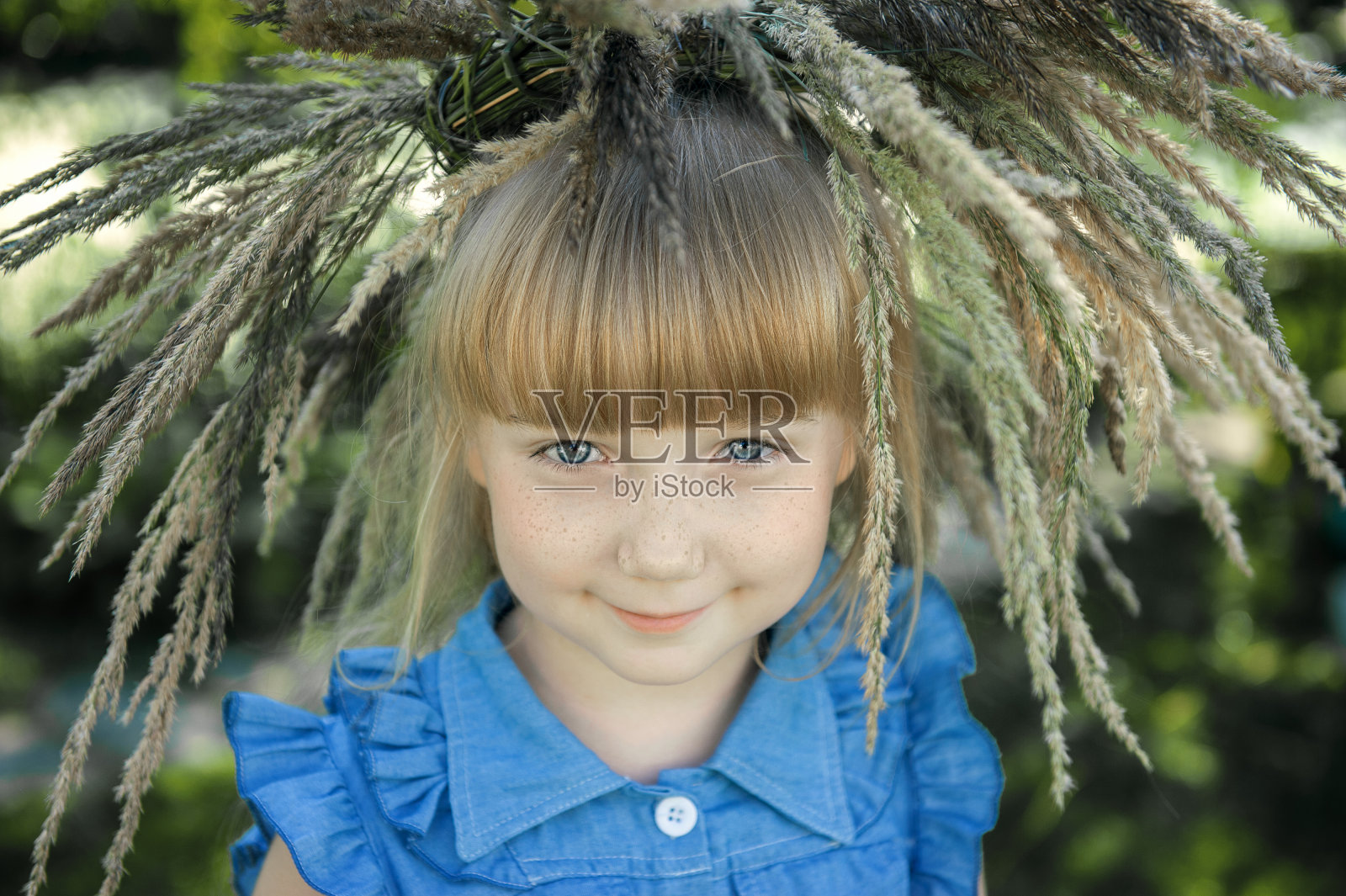 美丽的红发女孩，长着雀斑，头上戴着夏季草药花环，用蓝色的眼睛看着镜头。年轻美丽的女孩7-10岁在自然界照片摄影图片