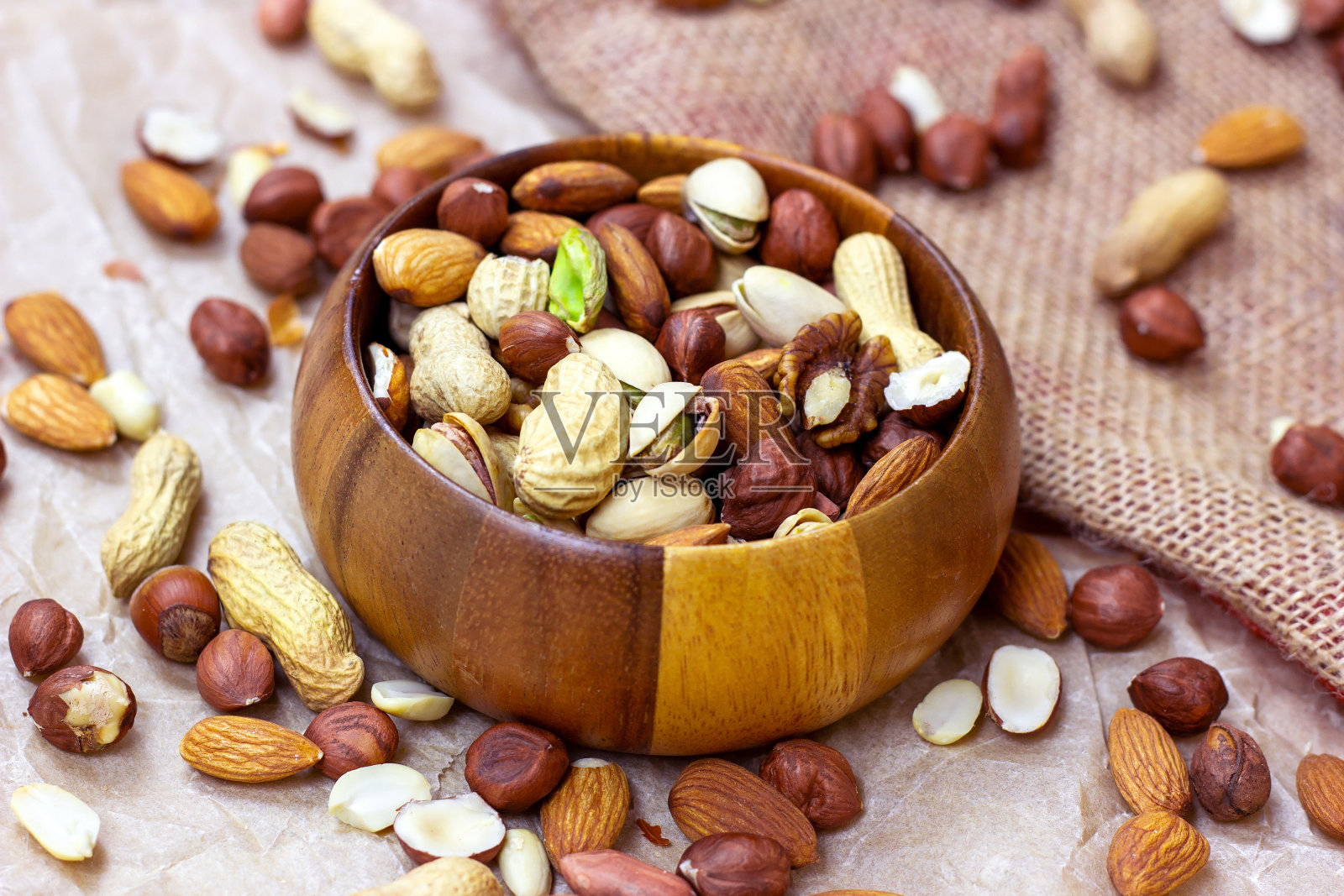 不同的坚果:杏仁，开心果，花生，榛子在木碗中，背景光线照片摄影图片