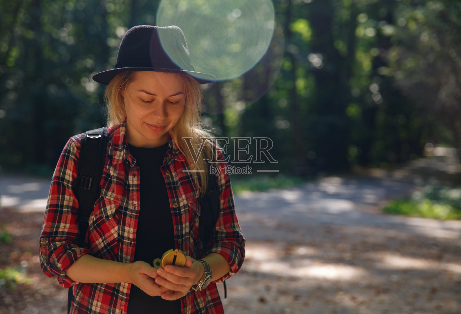 年轻的白人妇女戴着帽子看着她手中的指南针照片摄影图片