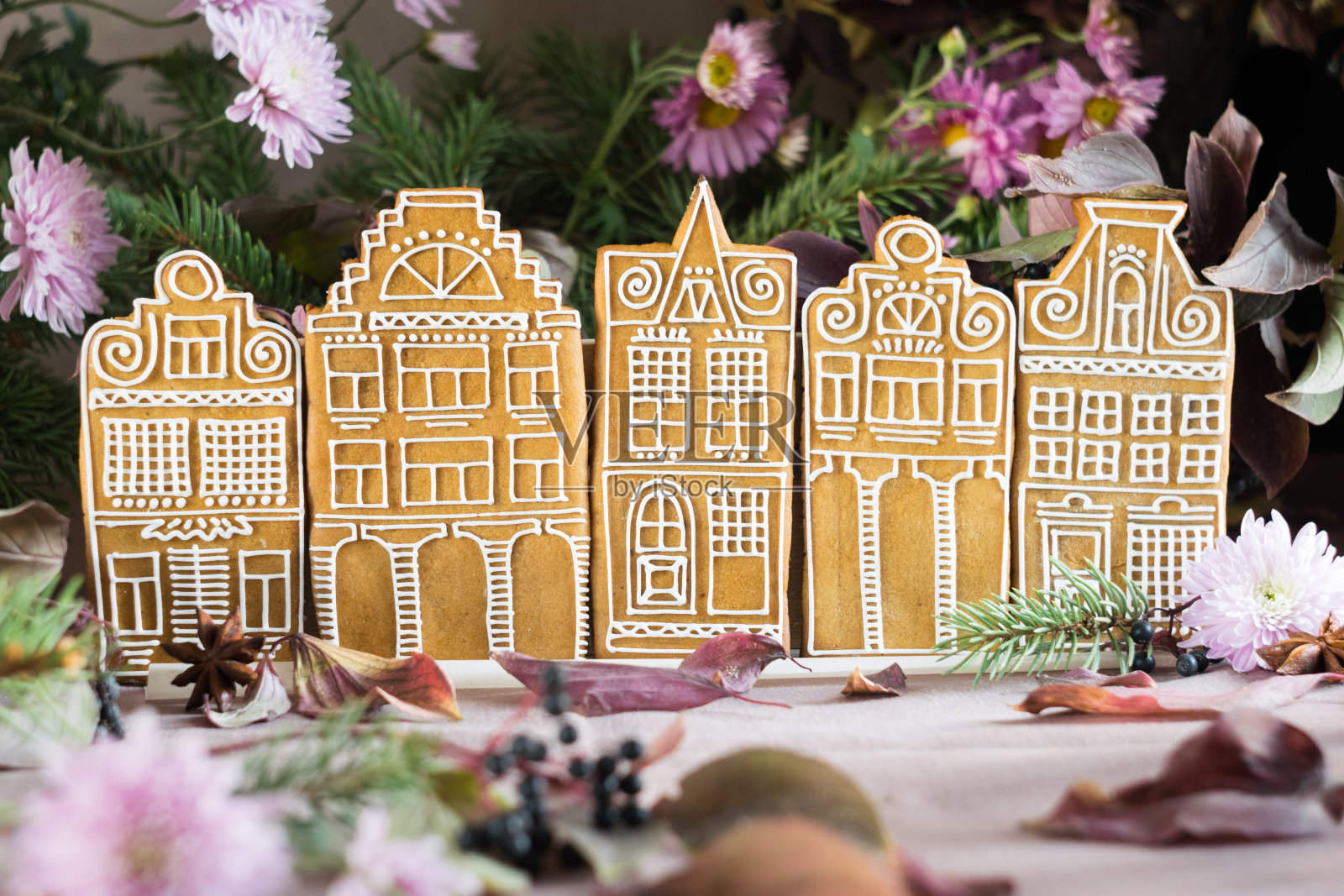 五座姜饼屋排成一排，后面是花和冷杉树枝。有选择性的重点照片摄影图片