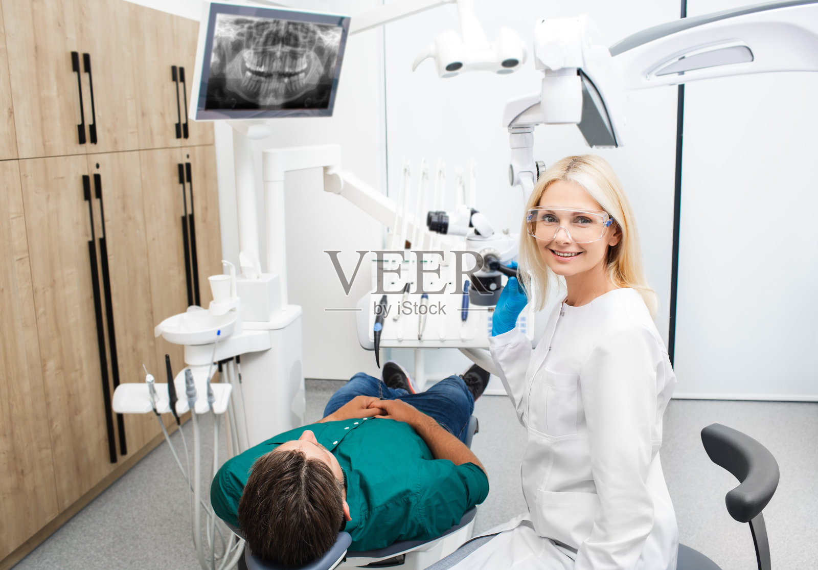 一个美丽的女牙医在医疗制服治疗病人在牙科诊所的肖像照片摄影图片