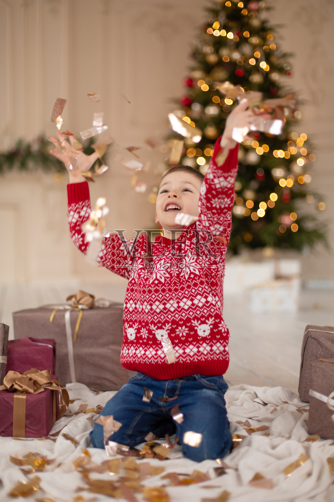 圣诞节主题儿童肖像：身穿红色毛衣的青少年在五彩纸屑中庆祝节日照片摄影图片