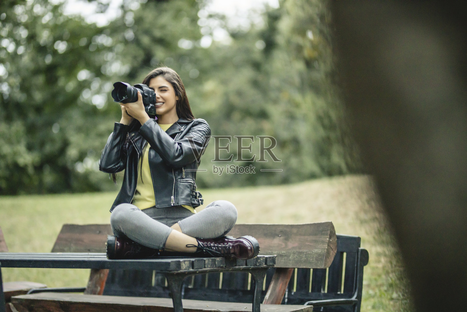 一位年轻的女摄影师正在室外用她的相机拍照照片摄影图片