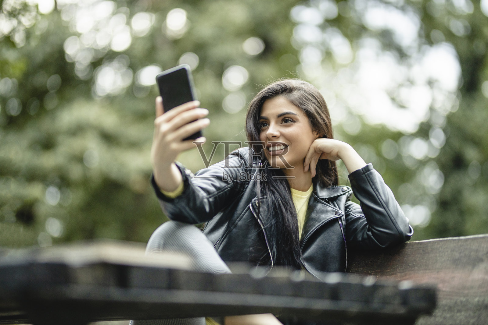 年轻美丽的女人使用电话，有视频电话和享受在自然照片摄影图片