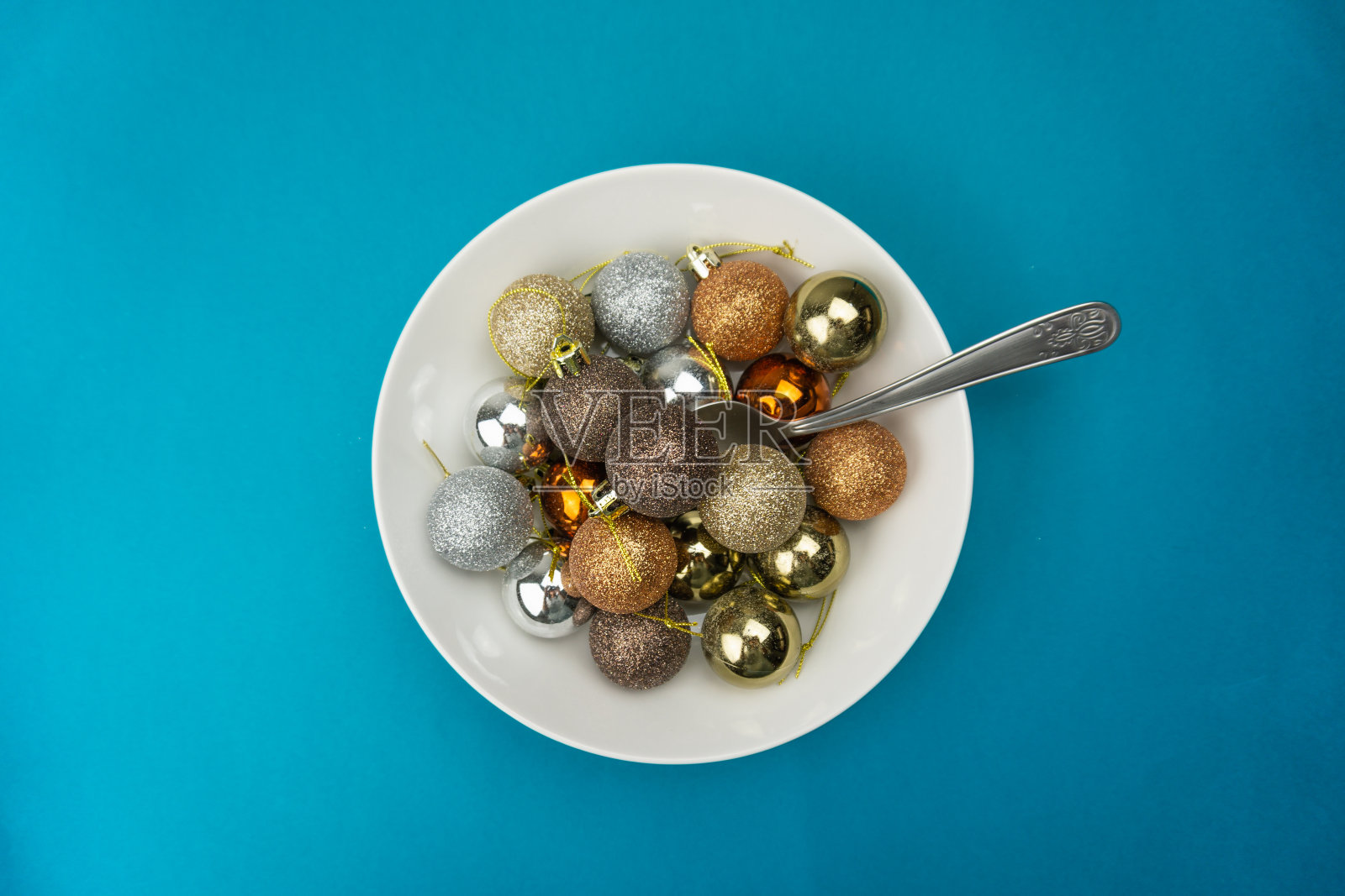 一个白色的盘子装满了圣诞球和勺子在一个蓝色的背景照片摄影图片
