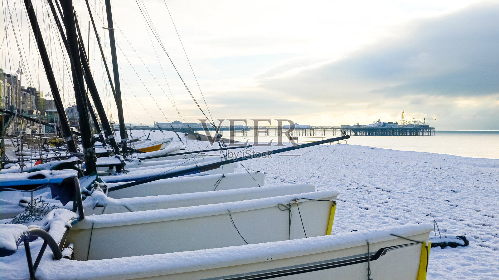 在一个冰雪霜冻的早晨，小帆船在卵石海滩上照片摄影图片