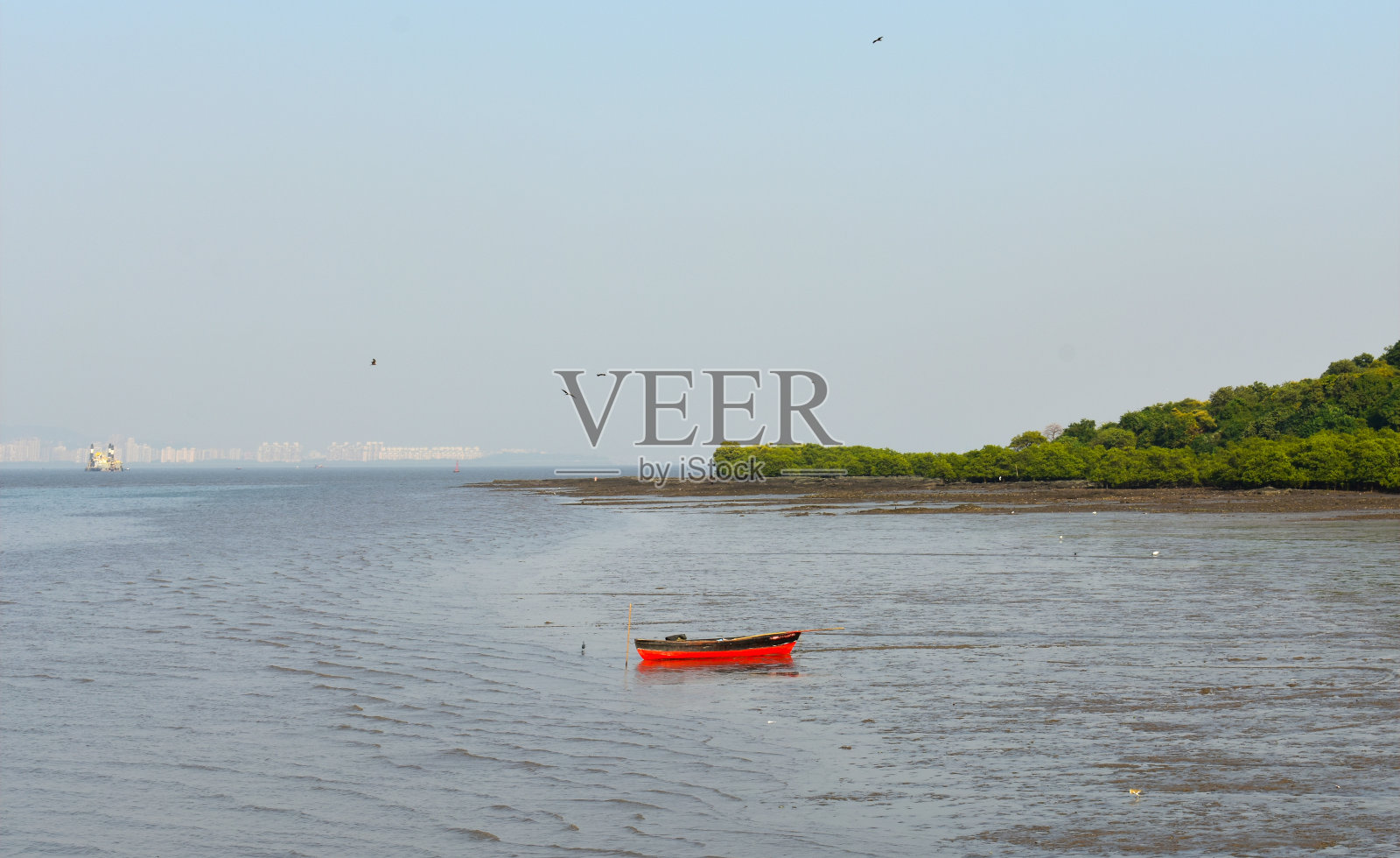 一只红色的小船停在孟买附近的水中央照片摄影图片