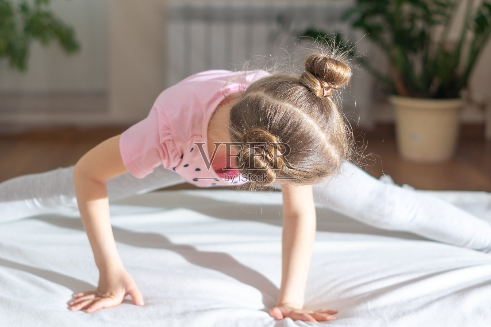 女孩在家里做体操和运动。执行横向缠绕。网络远程学习。闭关锁国则在摧毁隔离。好家的概念。照片摄影图片