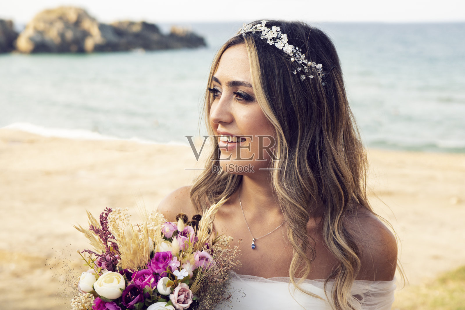 美丽的新娘捧着婚礼鲜花，迷人的女人穿着婚纱。新婚快乐的女人。新娘的婚礼妆容和发型。微笑的新娘。结婚的那一天。华丽的新娘。婚姻。照片摄影图片