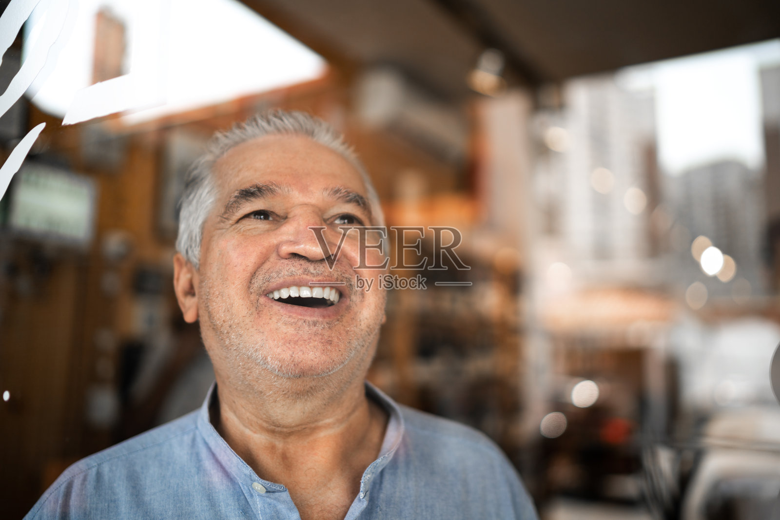 快乐的老年男人透过窗户看着他的小生意照片摄影图片