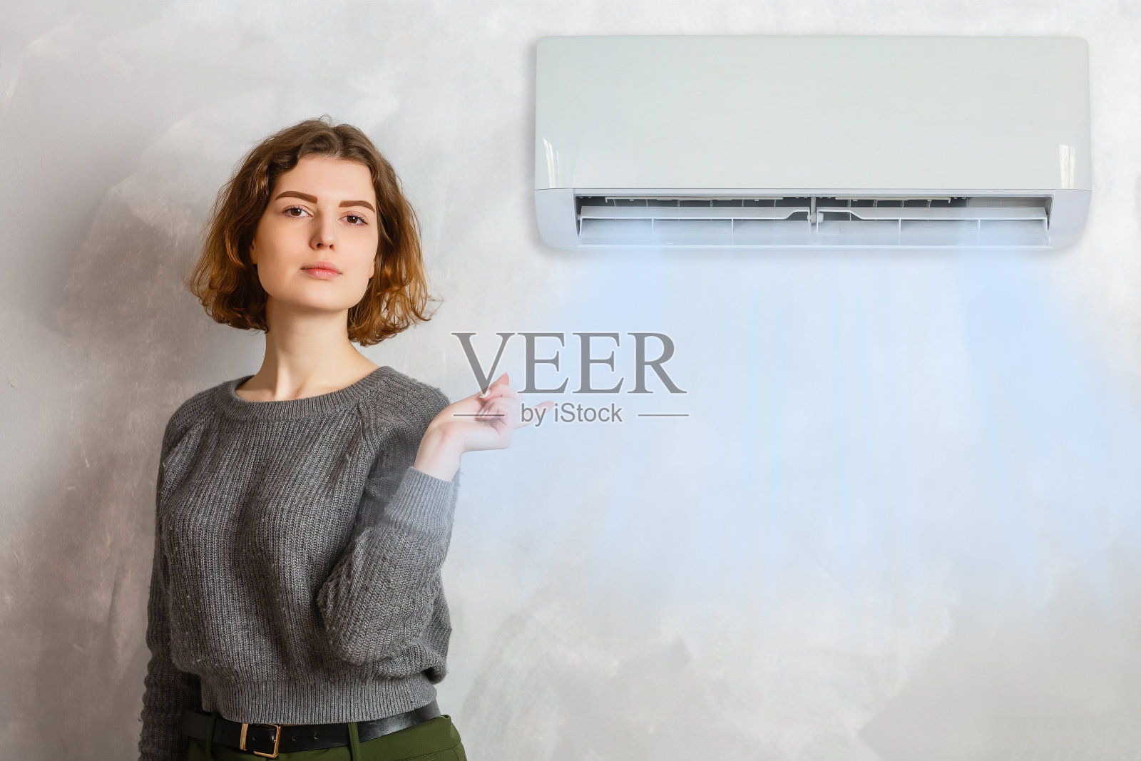 一个快乐的女人在家里的空调前拿着遥控器照片摄影图片