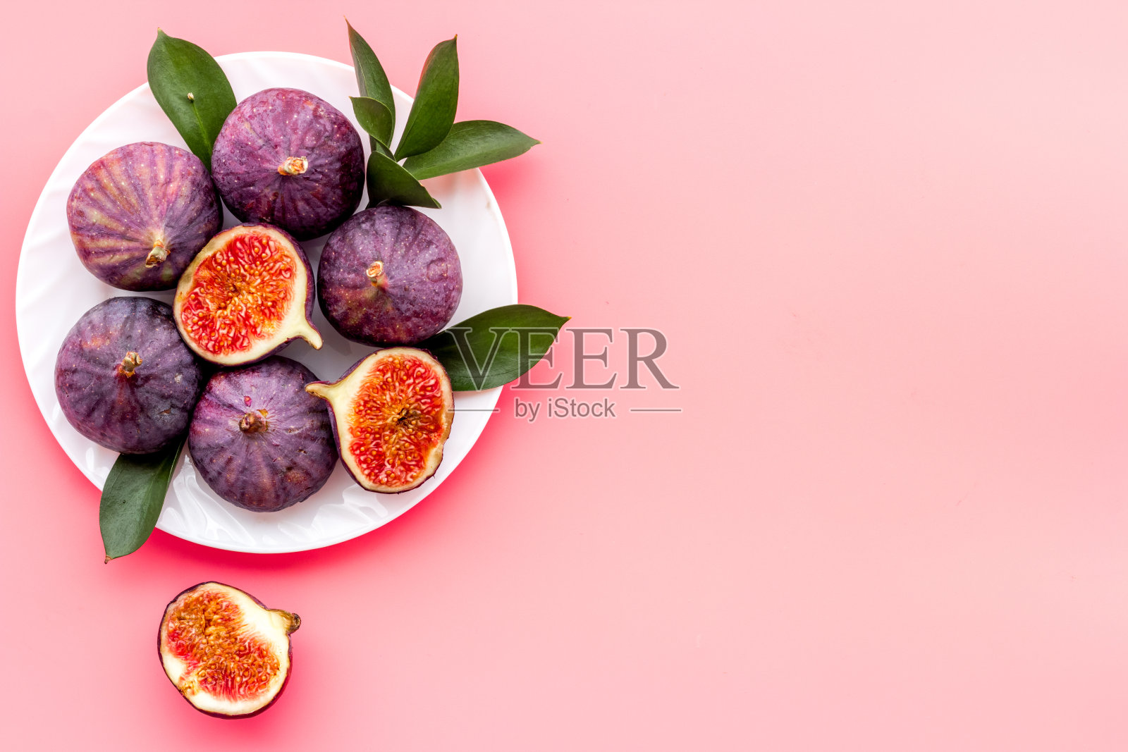 新鲜成熟的无花果和叶子放在盘子里。地中海水果背景照片摄影图片