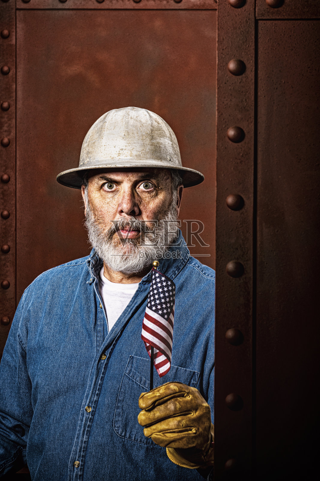 一名男性建筑工人举着一面小美国国旗的肖像照片摄影图片