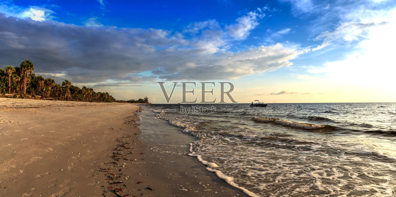 在黑暗的天空下，光脚海滩水域上的小船照片摄影图片