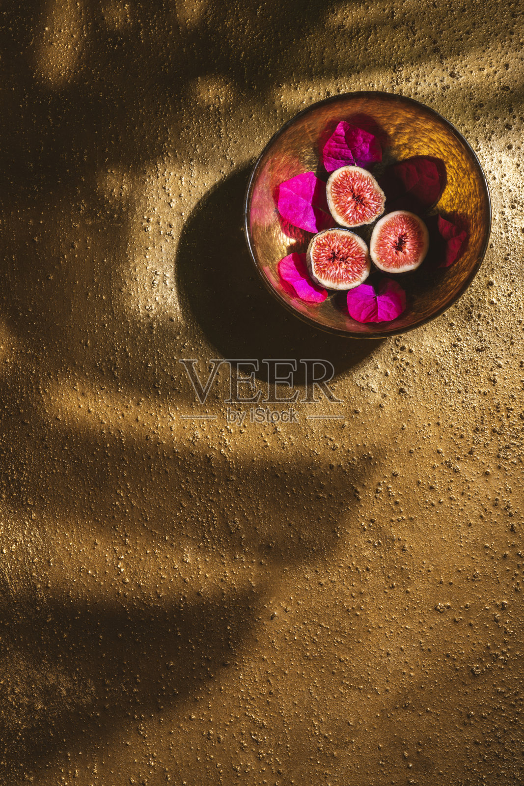 无花果果实切成一半，放在金色的碗里，在金色的背景上照片摄影图片