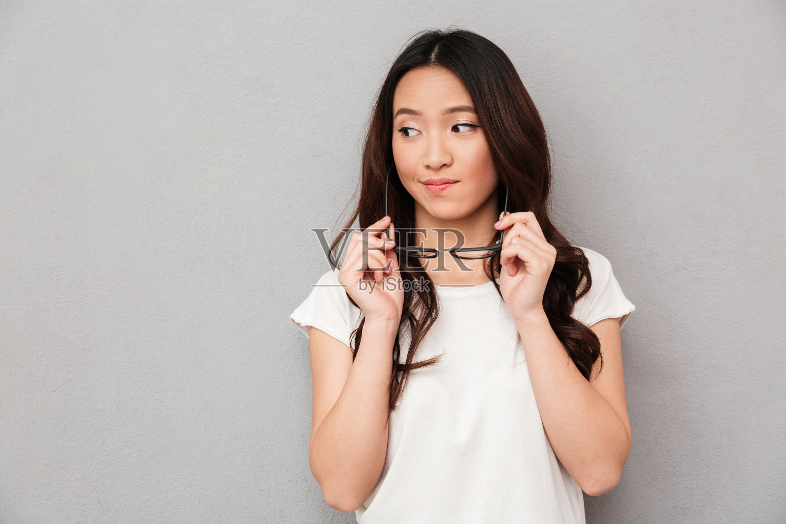 穿着t恤的亚洲女人拿着眼镜看向别处照片摄影图片