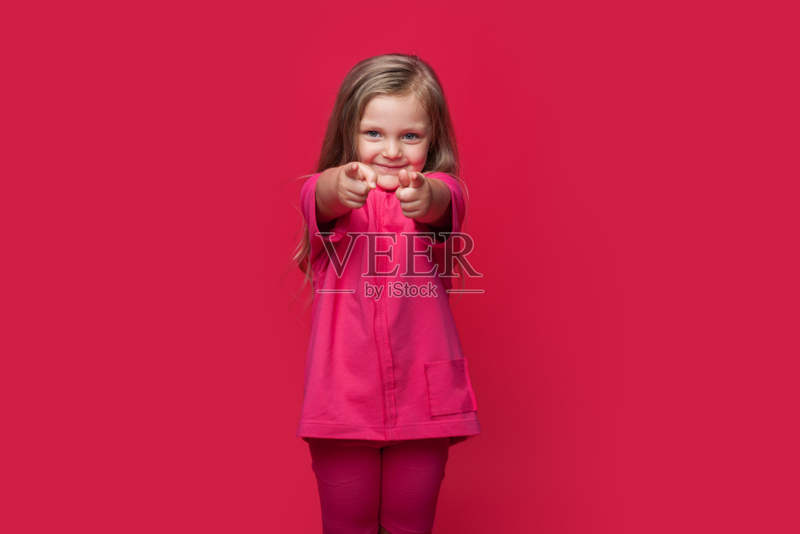 黑白照片，一个白人女孩指着相机在一个工作室的红色墙壁上照片摄影图片