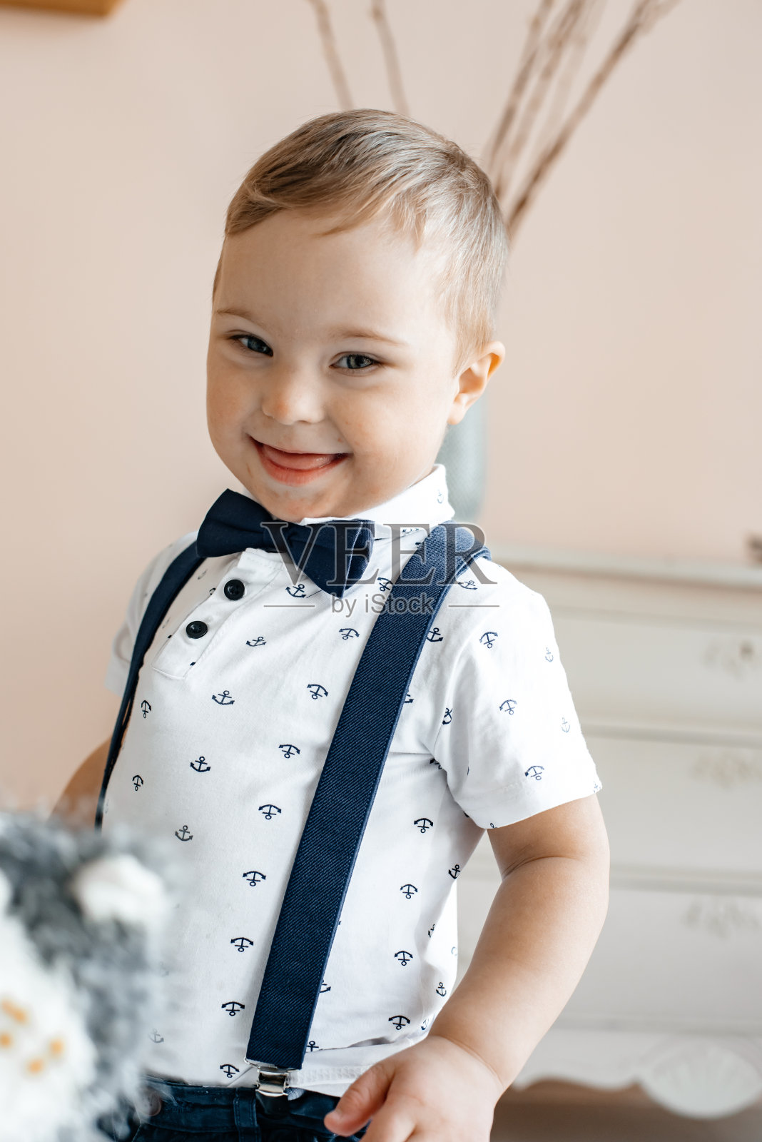 微笑的孩子穿着白色衬衫和裤子背带。照片摄影图片