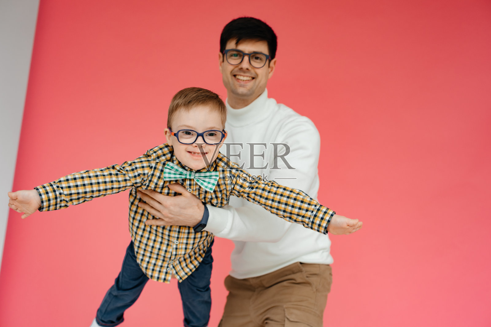 在演播室里，一位父亲抱着儿子玩。照片摄影图片