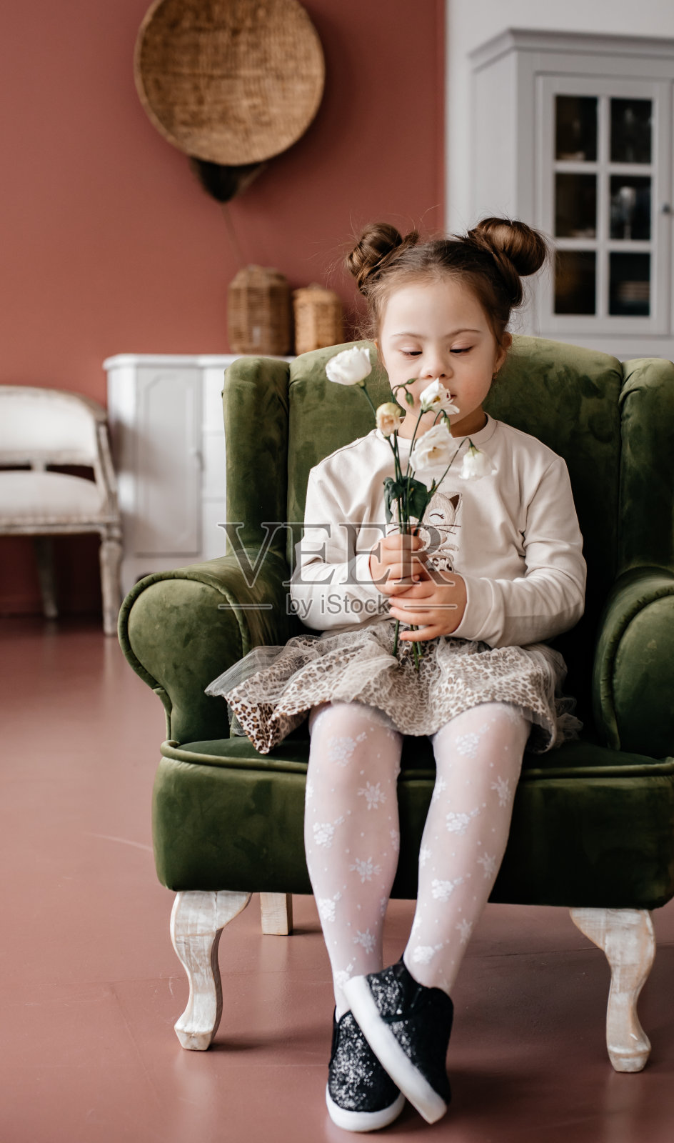 一个孩子坐在卧室的扶手椅上看花。照片摄影图片