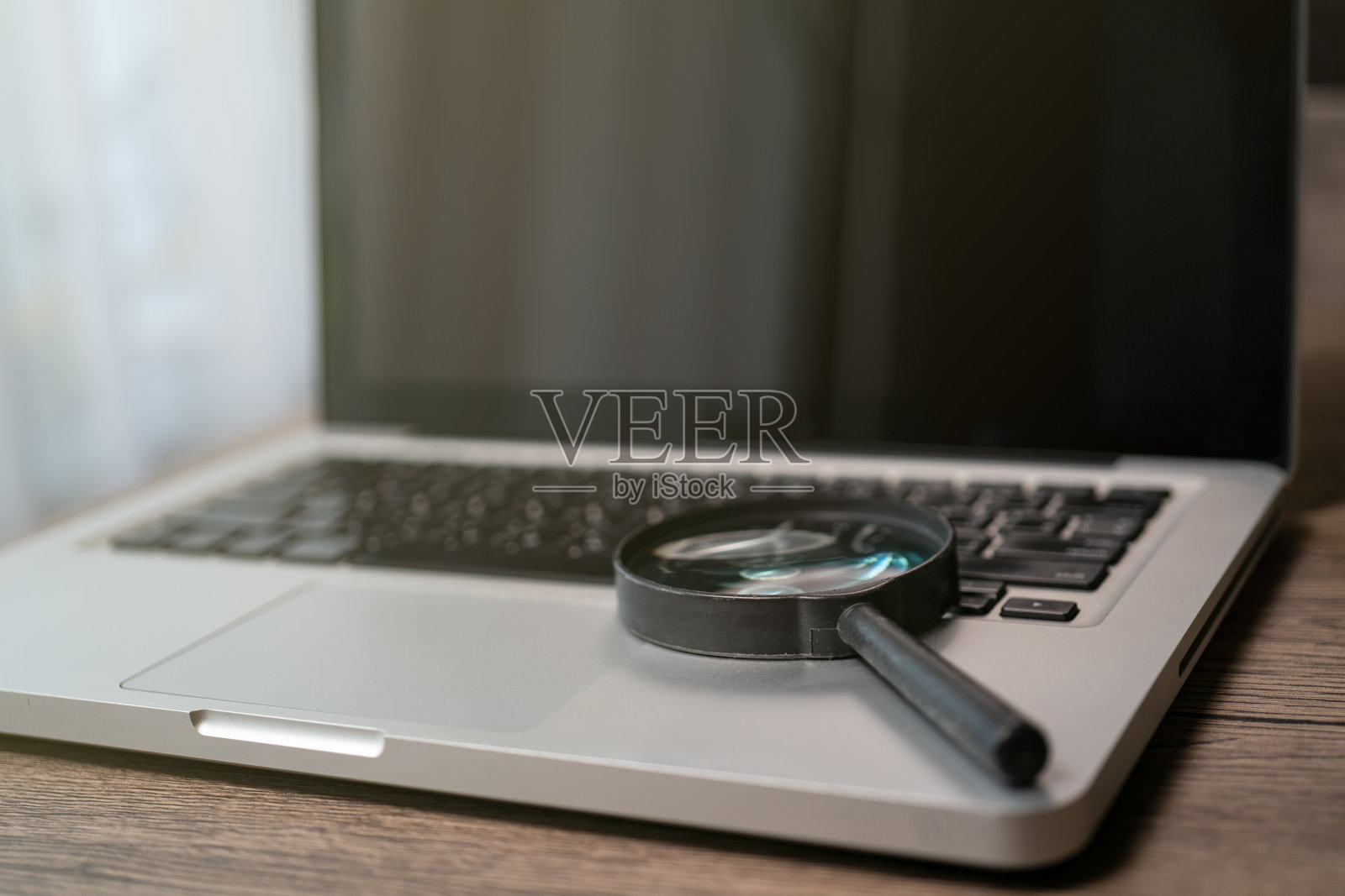 笔记本电脑用放大镜对笔记本电脑键盘，概念搜索。照片摄影图片