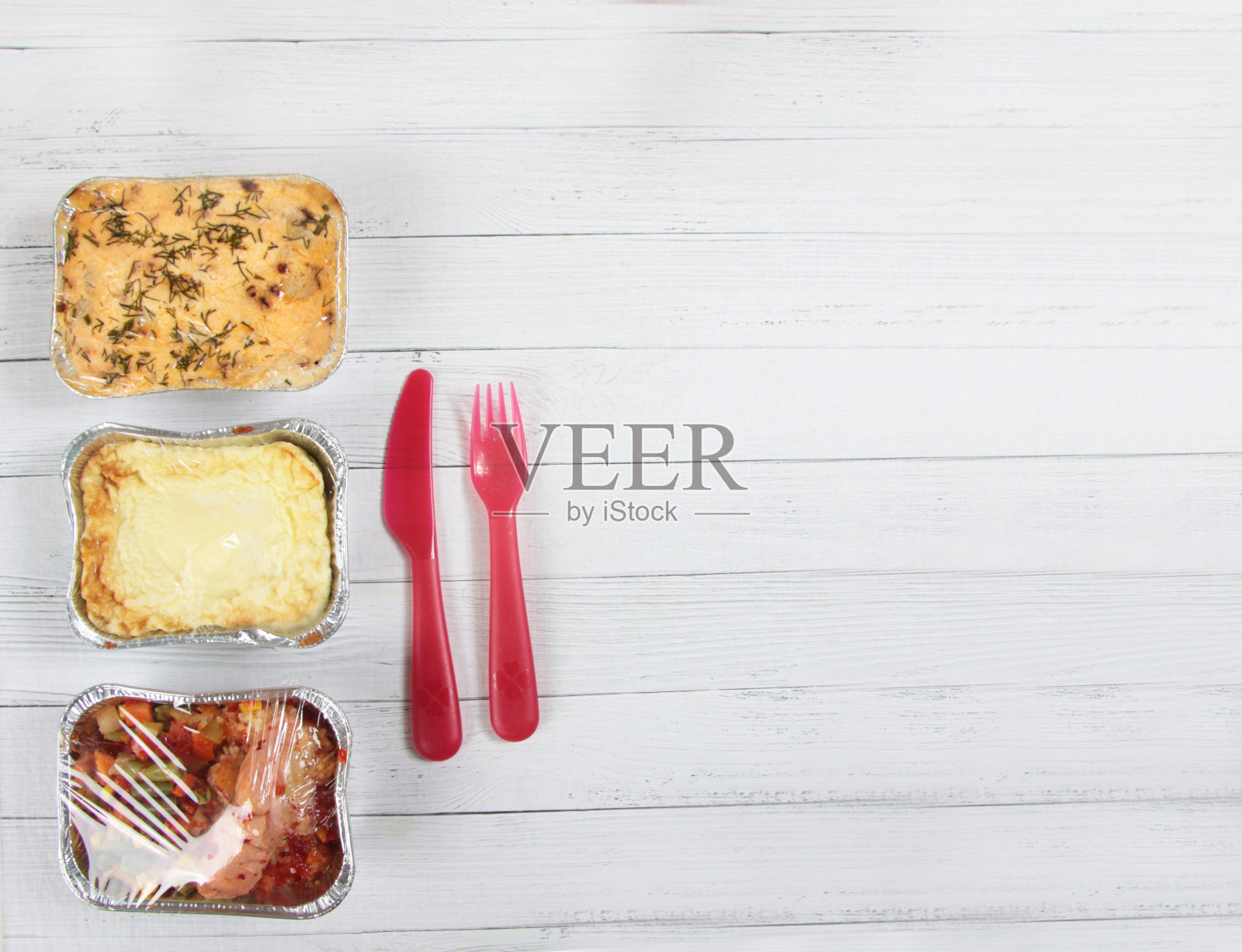 送货菜单概念-三箔盒与食物，塑料叉和刀孤立在白色木制背景平lay照片摄影图片