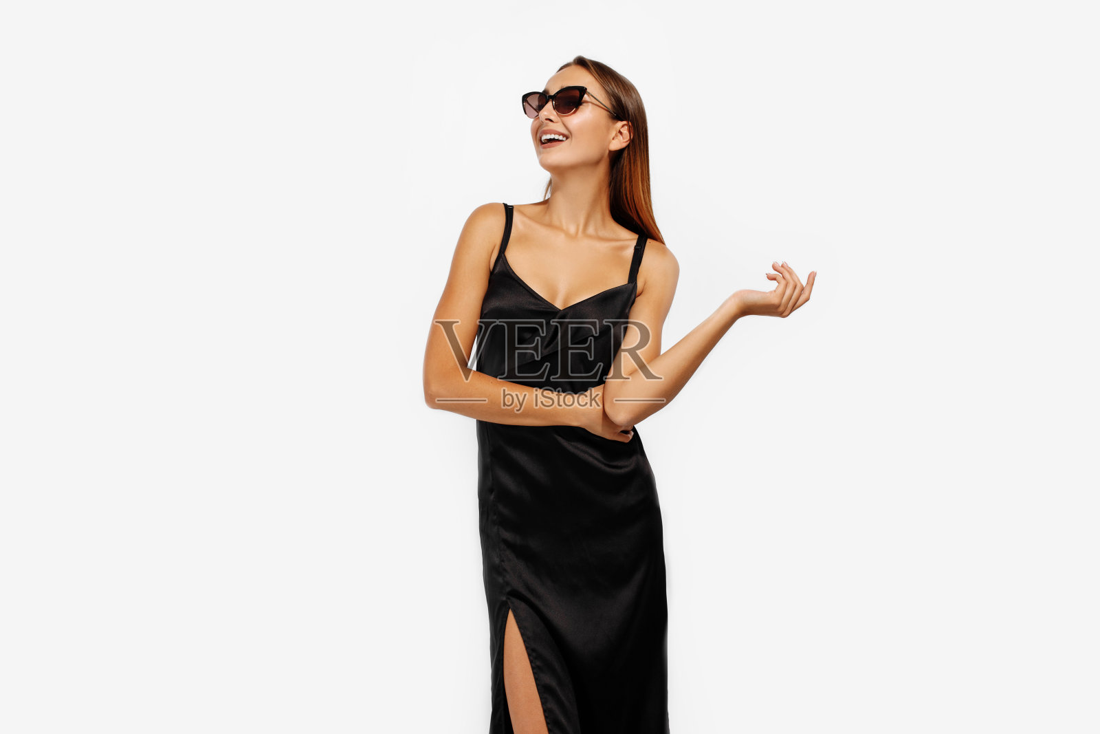 优雅快乐的年轻女子戴着墨镜和黑色的连衣裙，在白色的背景照片摄影图片