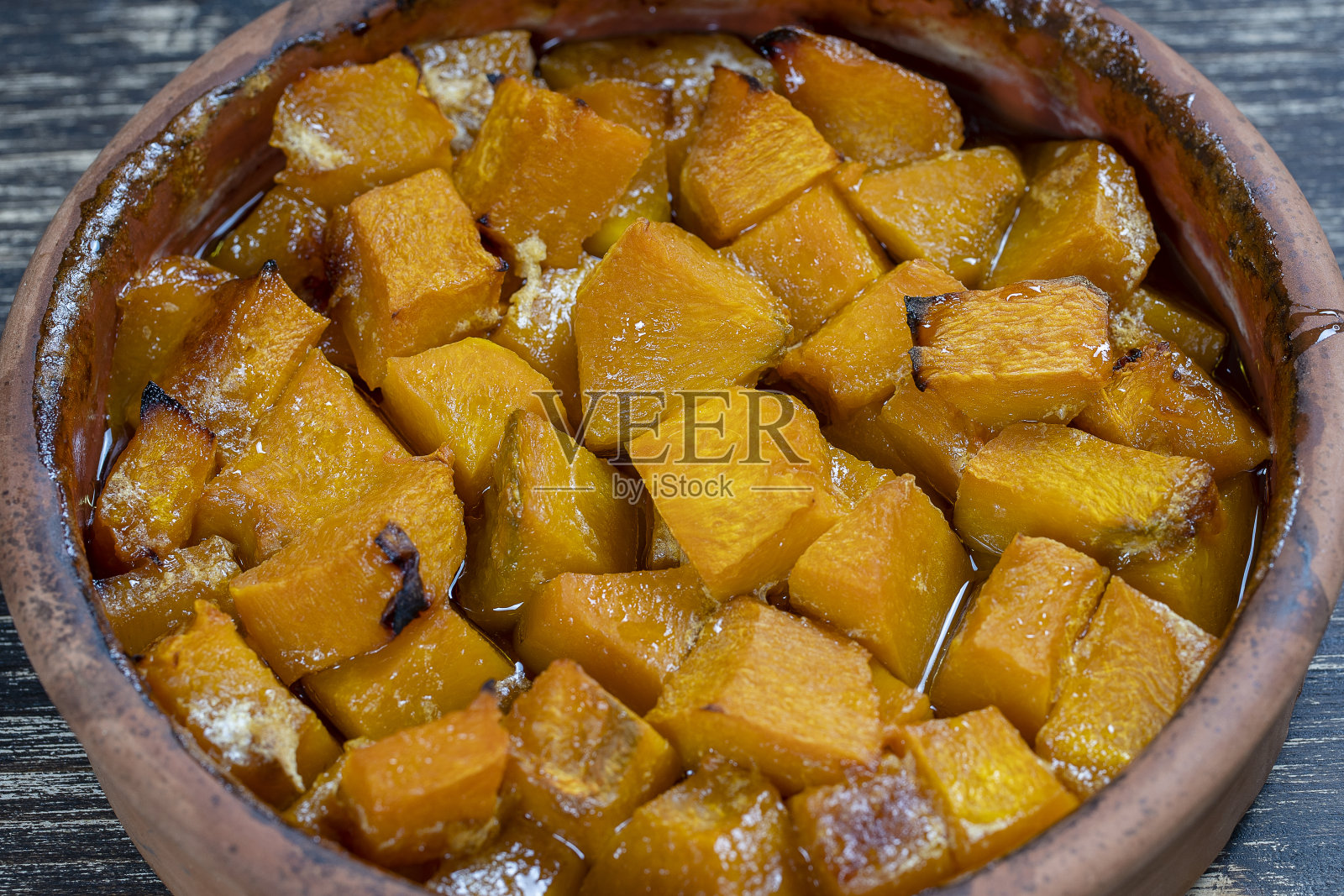 木桌上放着烤好的黄色南瓜，配上蜂蜜、橄榄油和香料。素食。特写镜头照片摄影图片