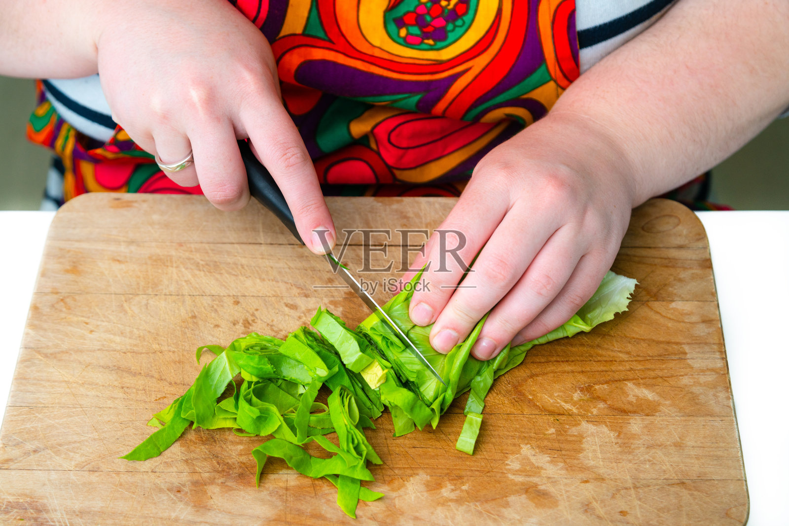 近距离观看厨师在木切板上切绿菠菜。在家做健康沙拉照片摄影图片