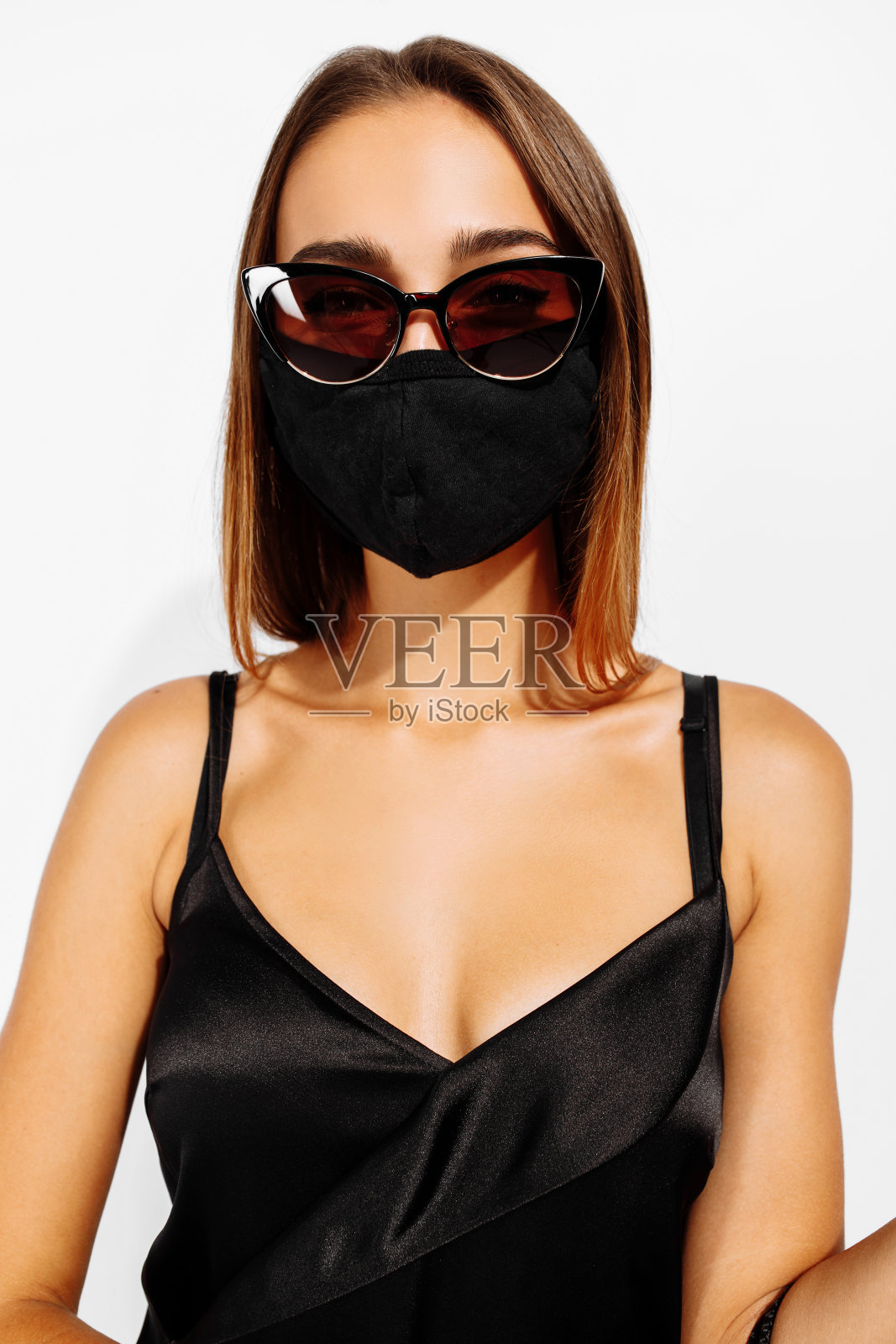 优雅的年轻女子戴着墨镜和黑色的衣服，在白色的背景照片摄影图片