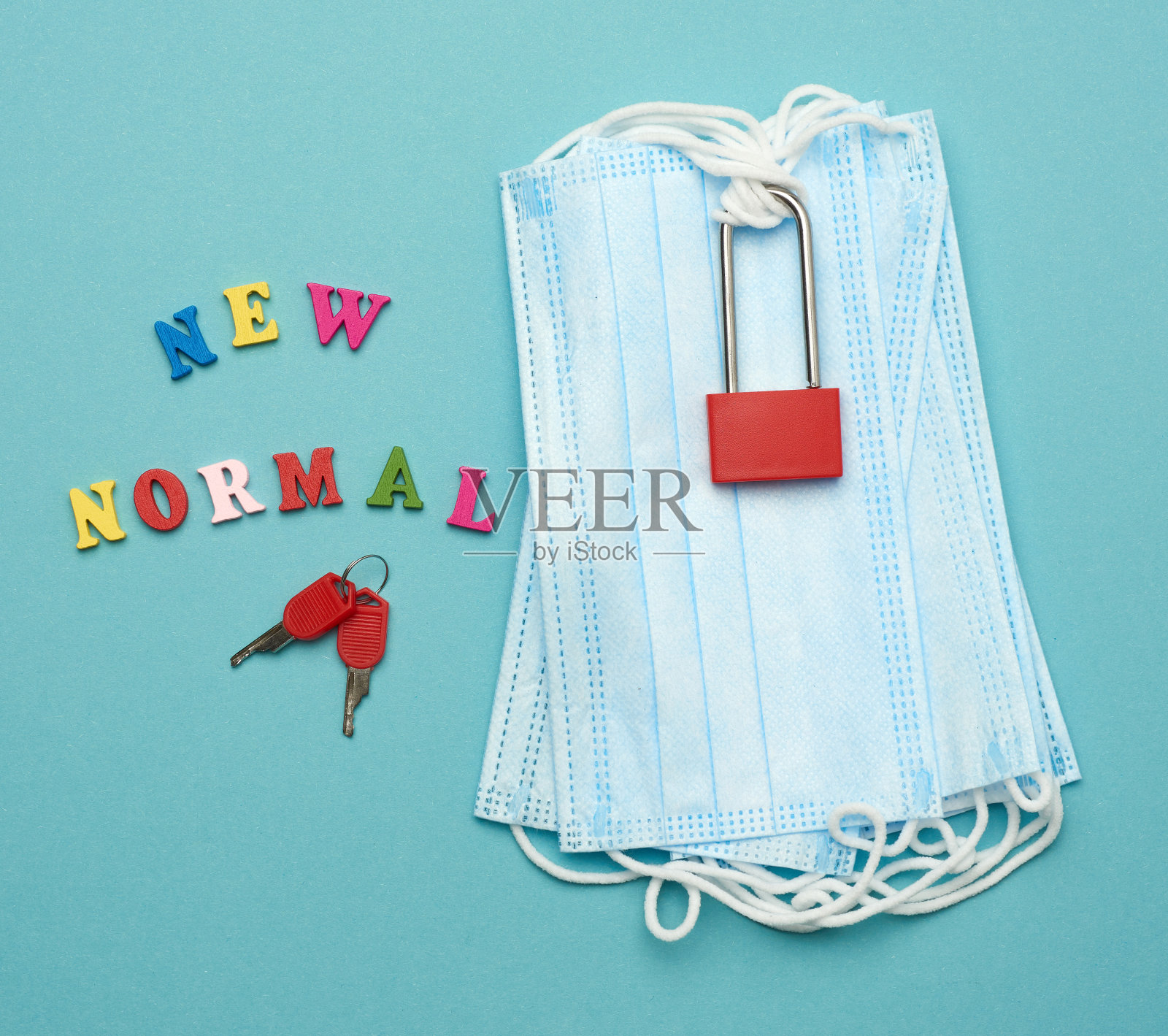 一堆一次性口罩和蓝色背景上的金属锁照片摄影图片