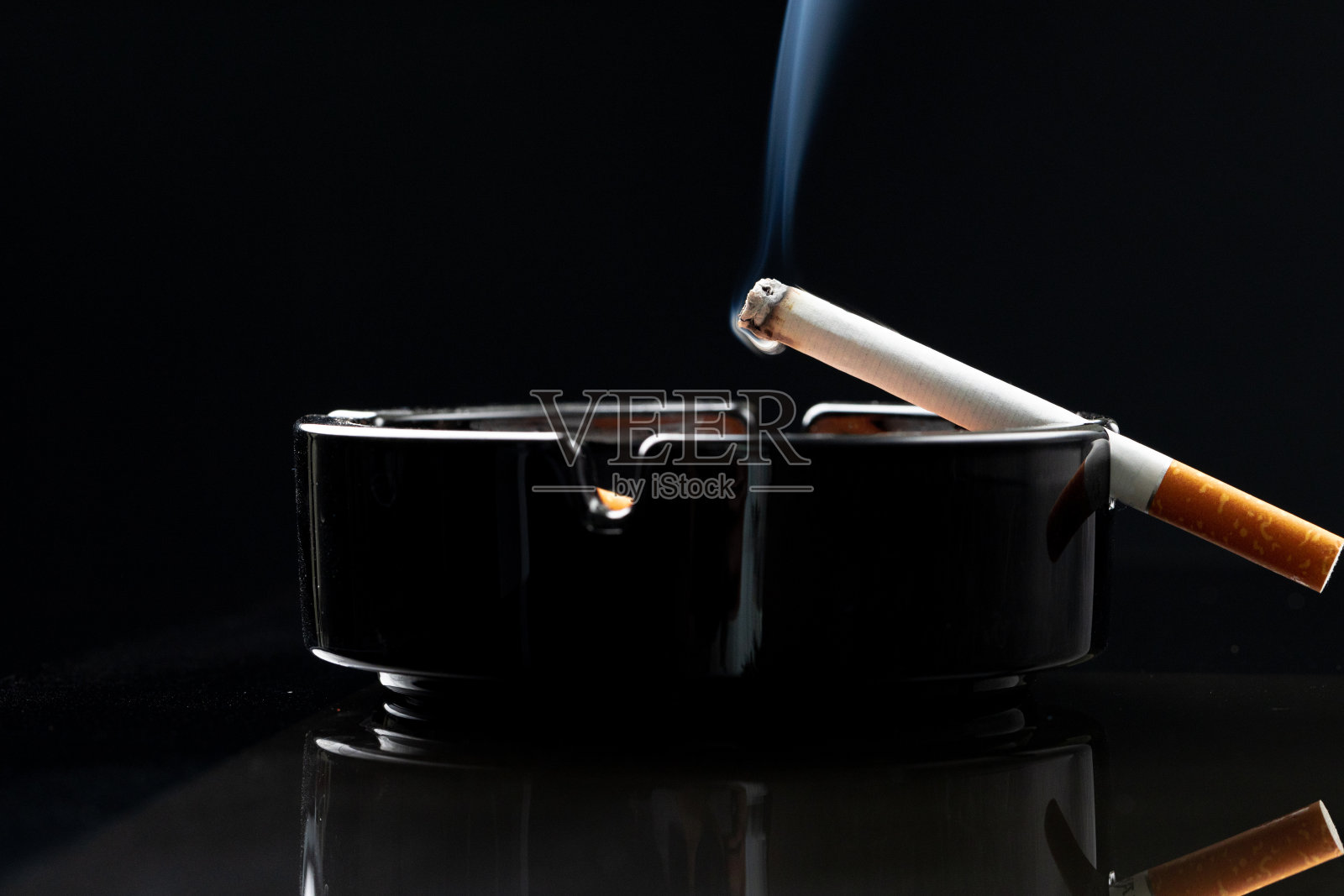 在黑色烟灰缸里燃烧着香烟照片摄影图片