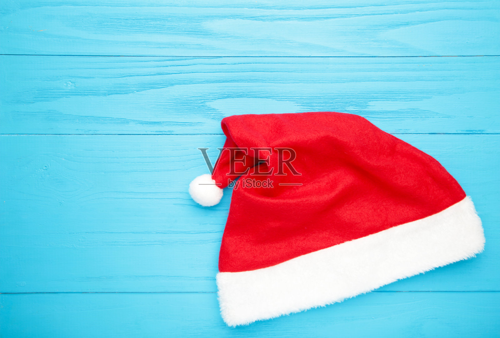 圣诞老人的帽子放在有复印空间的蓝色木桌上照片摄影图片