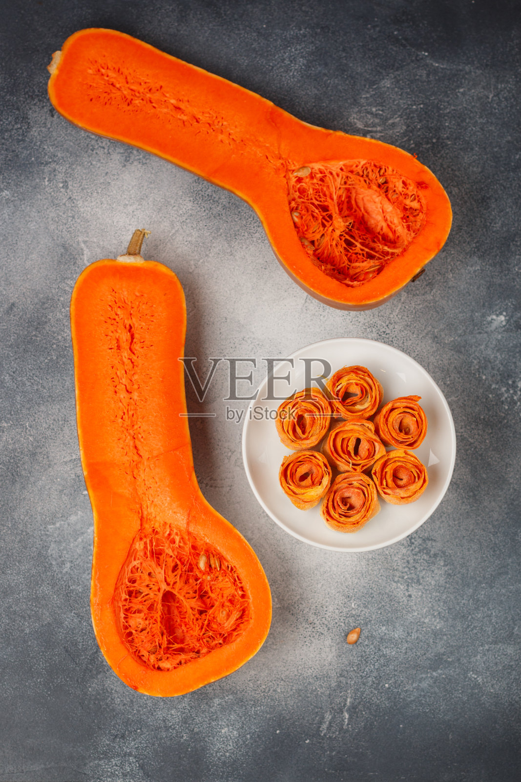 自制的有机脆南瓜片放在白色的盘子里，背景是灰色的。蔬菜玫瑰花朵。美味健康的素食(纯素)食品的概念。饮食小吃。选择性聚焦，复制空间照片摄影图片