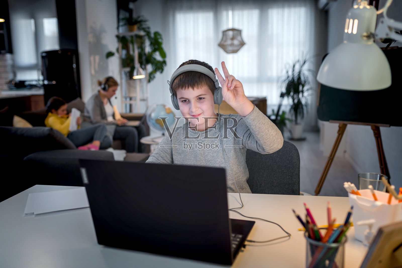 可爱的男孩戴着耳机用笔记本电脑进行在线学习。家庭学校。孩子在家里做作业。家庭教育的生活方式概念照片摄影图片