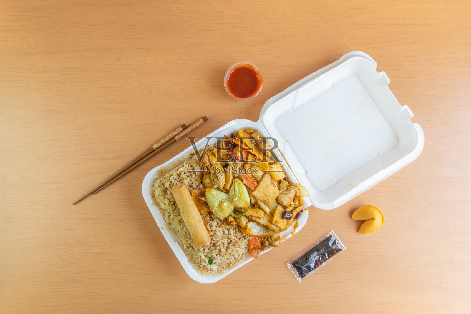 中式外卖食品，装在一次性容器里，里面有炒饭、鸡肉、蔬菜、中式棒子、酱油和西拉查照片摄影图片