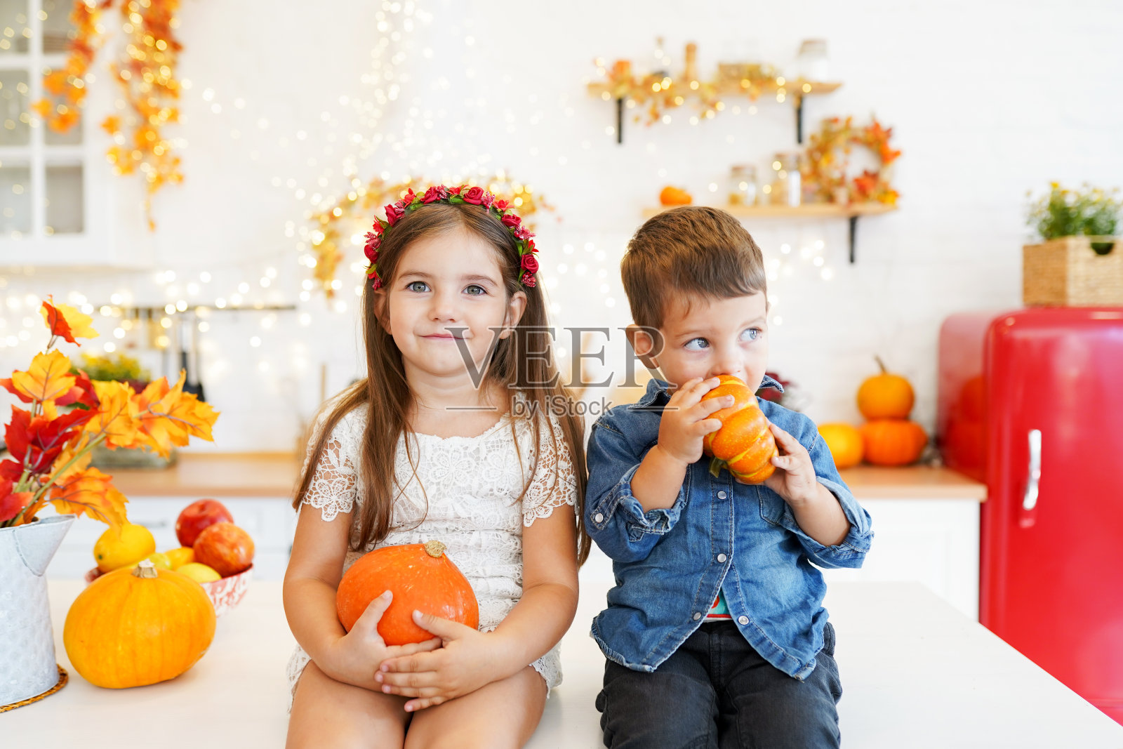 可爱的小朋友们正坐在秋天厨房的桌子上雕刻南瓜。快乐的一家人在为万圣节做准备。家里有有趣的孩子。照片摄影图片