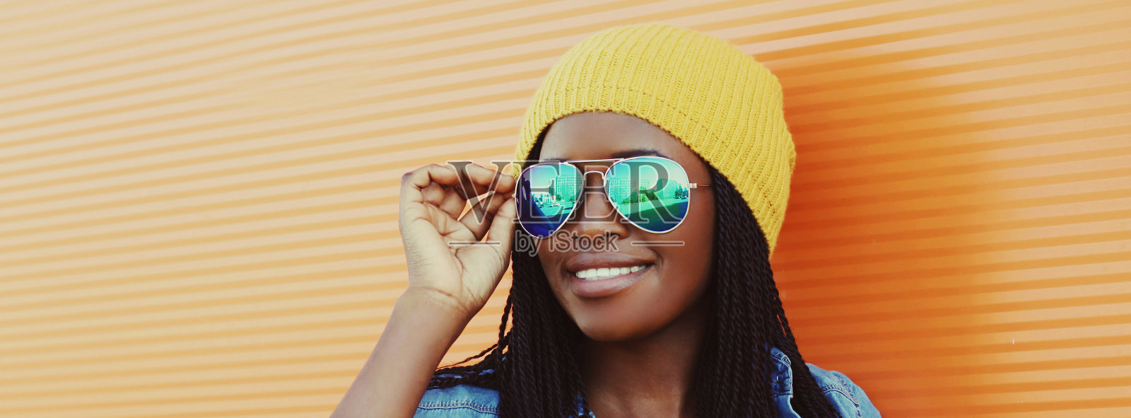 肖像快乐的年轻微笑非洲妇女戴太阳镜在休闲橙色城市背景照片摄影图片