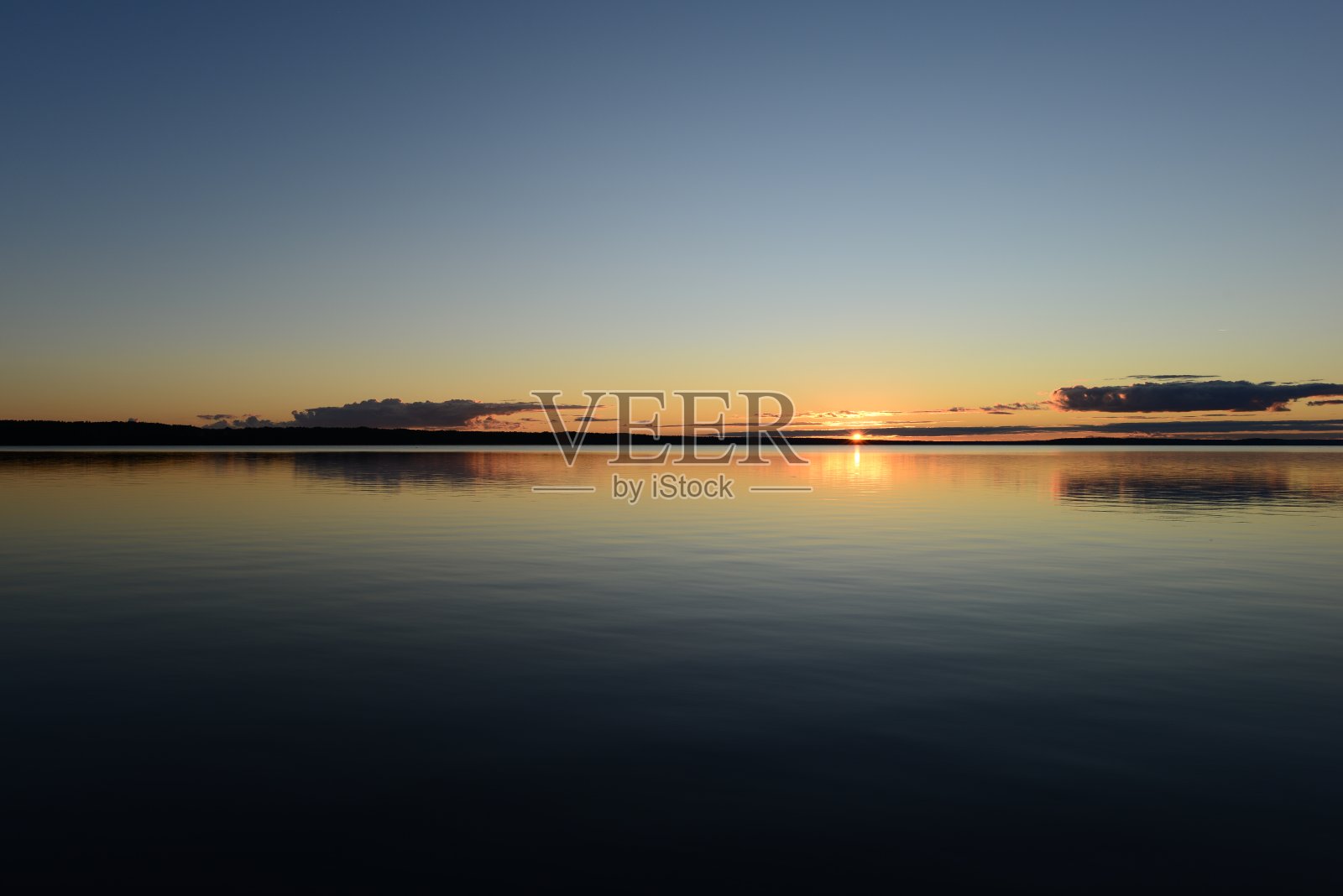 日落在平静的湖面上的地平线上照片摄影图片