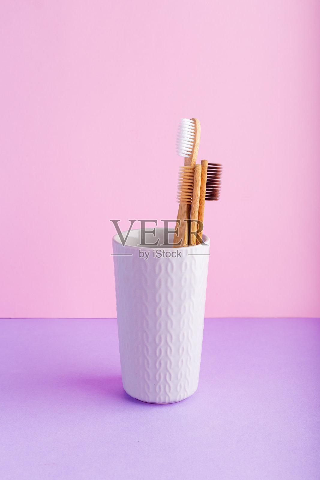 天然竹牙刷玻璃，粉红色背景。天然可降解竹牙刷。环保，零浪费，牙科保健，无塑料的理念照片摄影图片