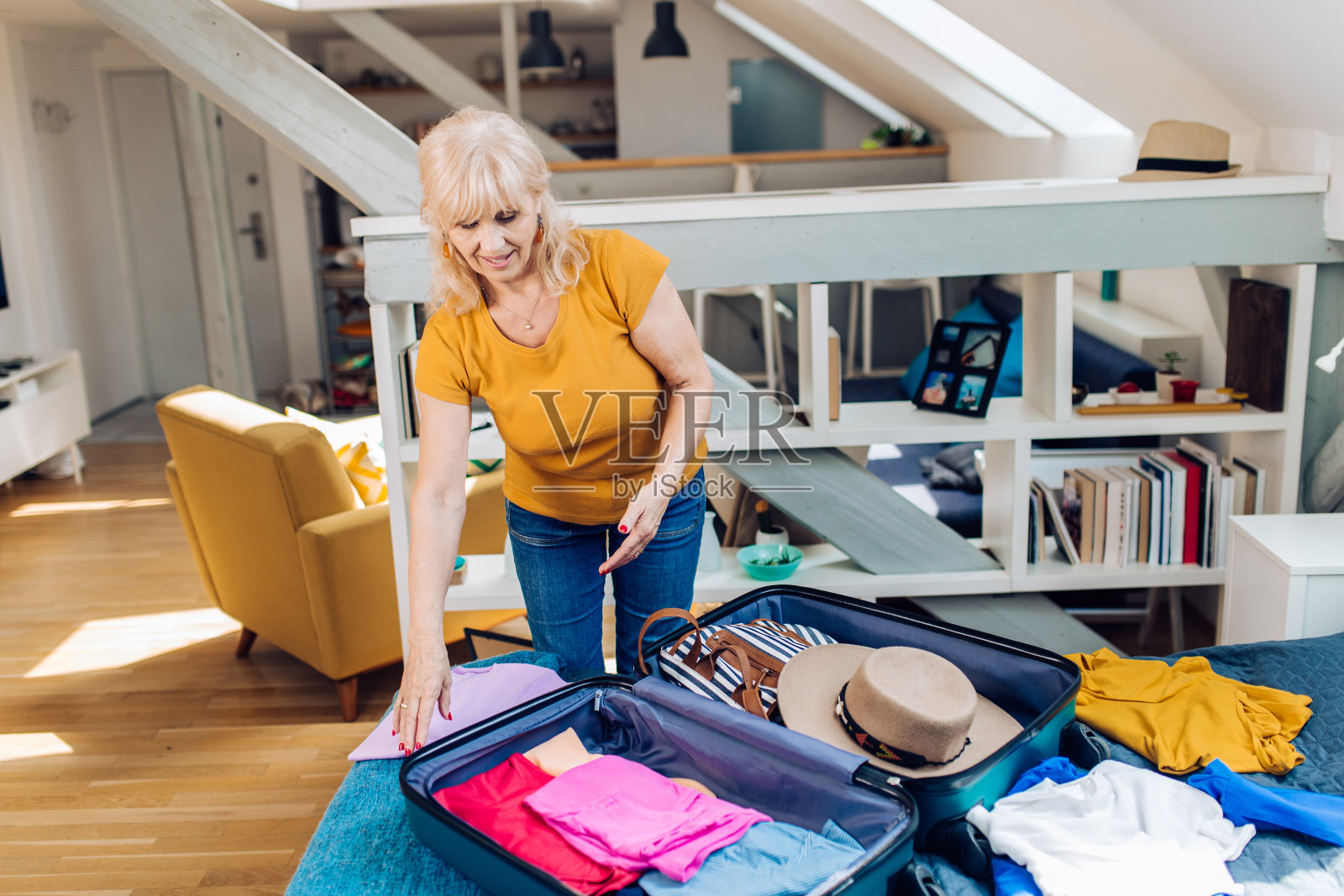 一个成熟的女人在收拾她的行李箱，准备去旅行照片摄影图片