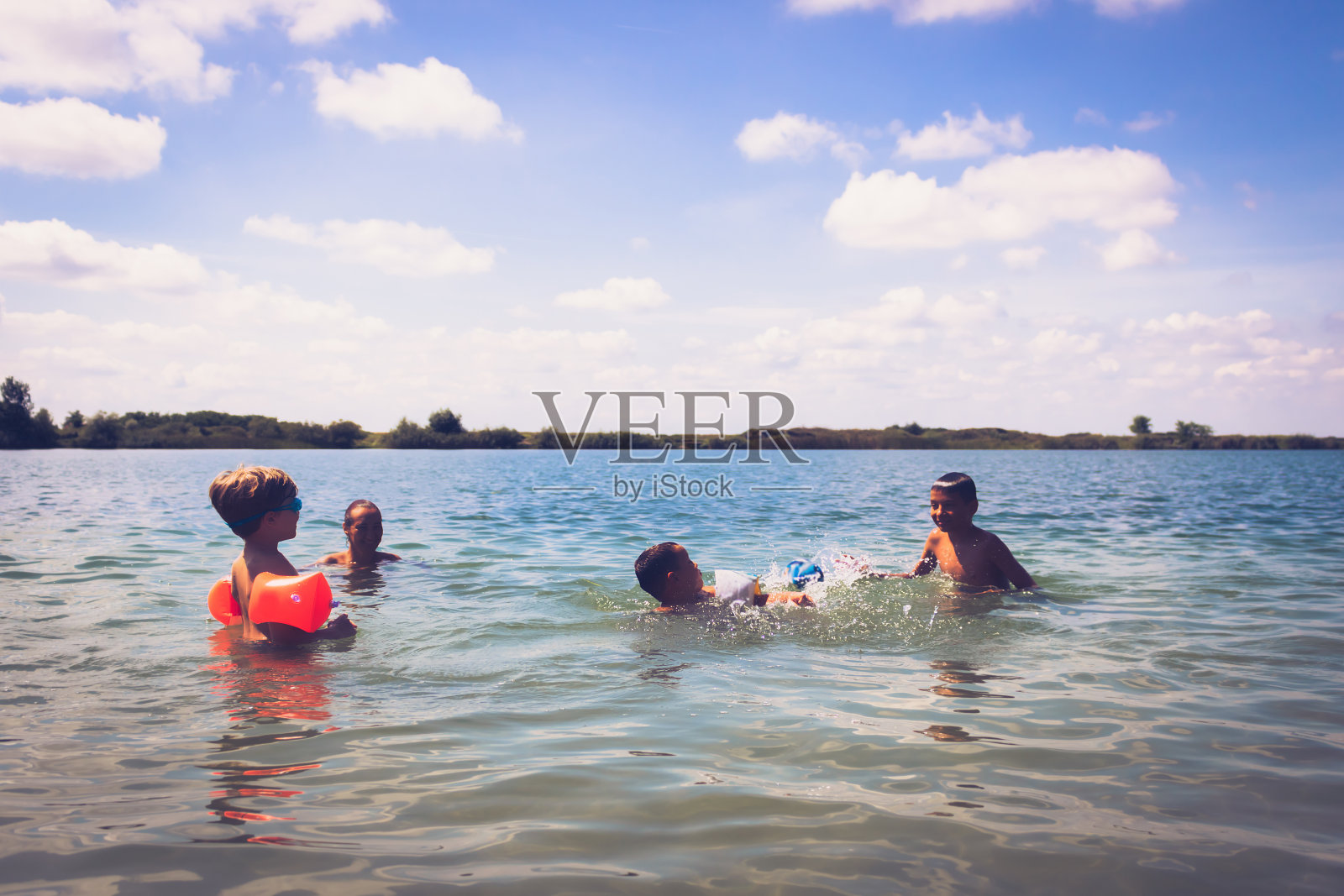 快乐的孩子们和妈妈在海滩的水里玩。照片摄影图片