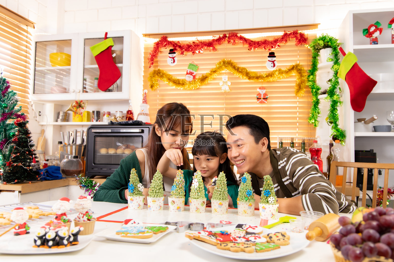 感恩节或圣诞节庆祝亚洲家庭晚餐概念。家人一起吃节日晚餐。快乐的家庭烹饪派对。爸爸妈妈和女儿，在家里吃晚饭。照片摄影图片