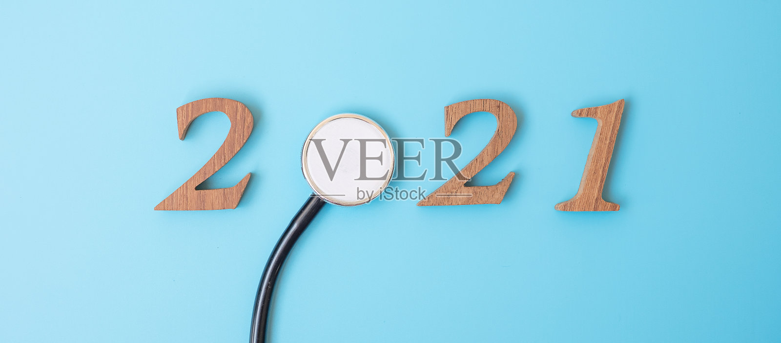 2021年，祝医疗保健、健康和医疗理念新年快乐。听诊器和木质号码在蓝色背景上照片摄影图片