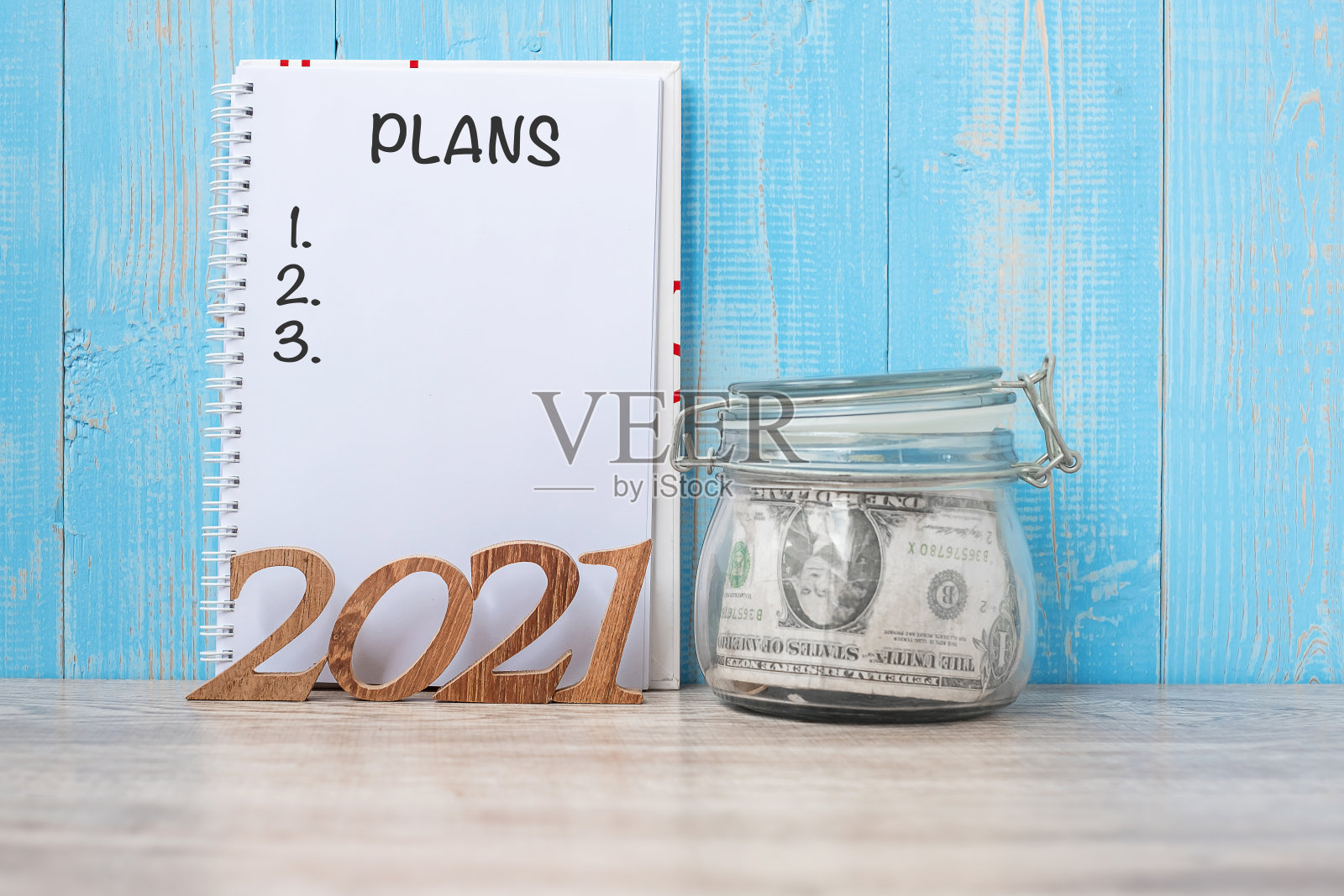 2021年新年有钱玻璃罐和木号。财务，决议，目标，计划和储蓄的概念照片摄影图片
