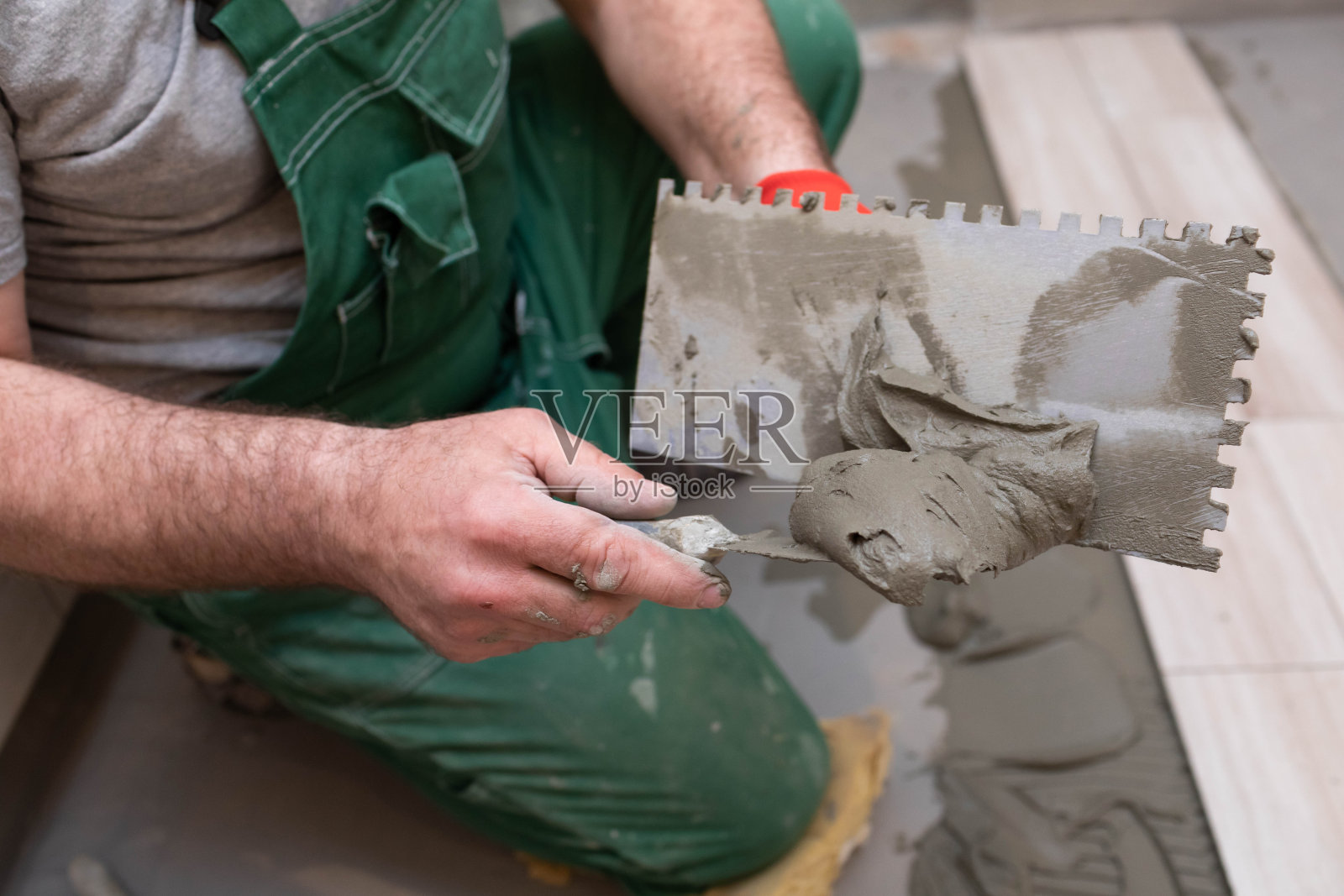 在浴室里铺陶土。建筑工人在工作。瓷砖用粘合剂。照片摄影图片