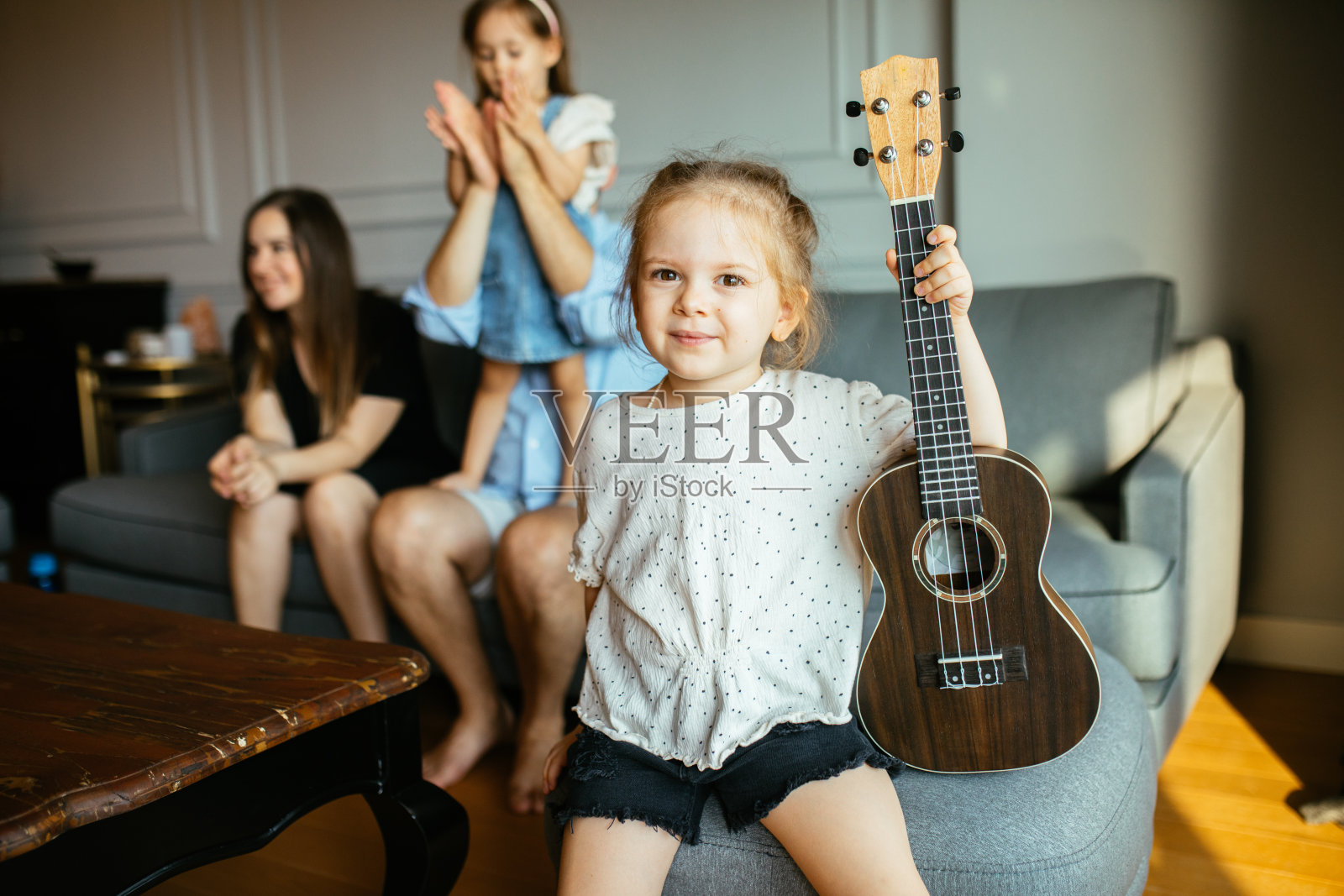 快乐的小女孩微笑着弹奏尤克里里在一个私人音乐学习课在家照片摄影图片