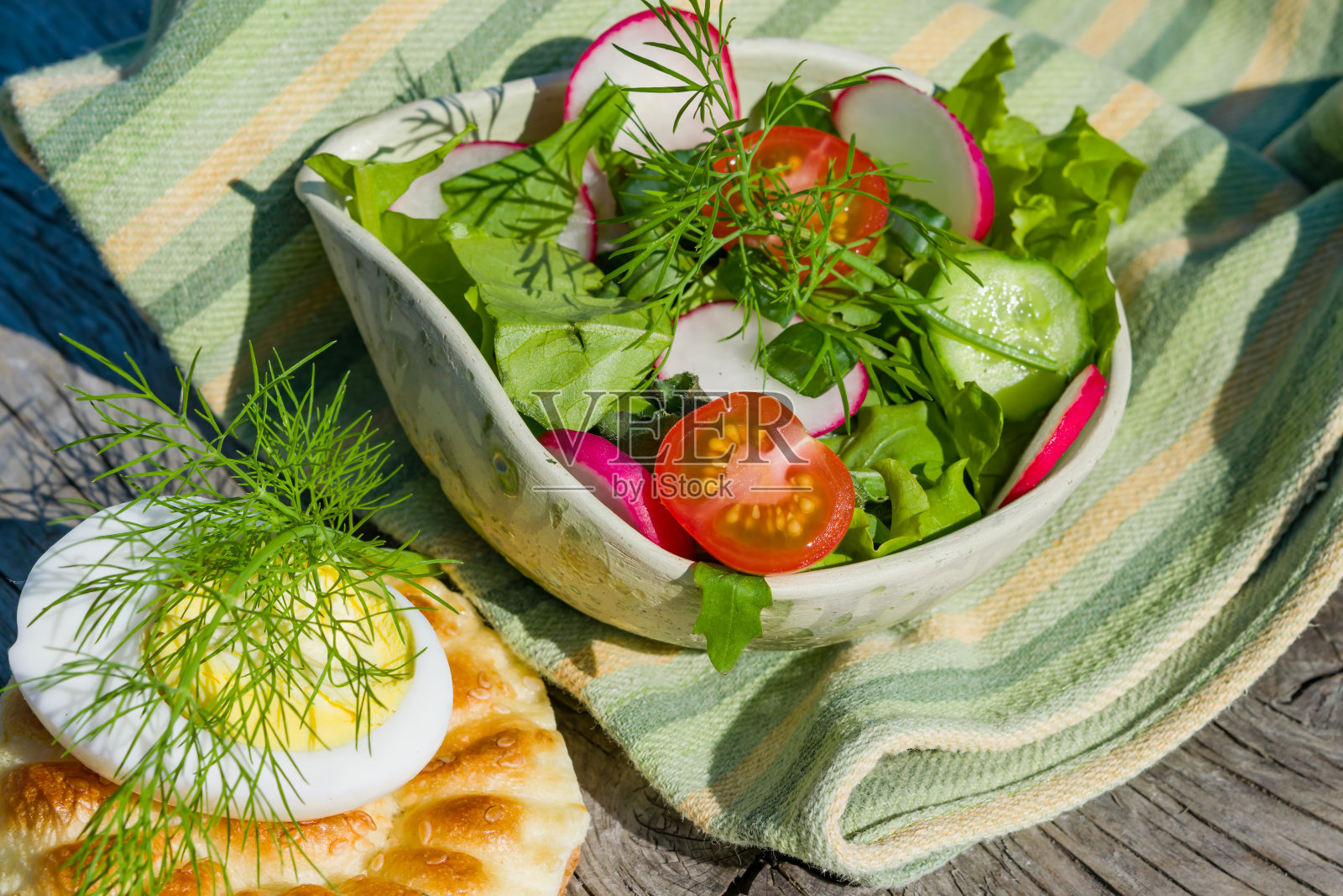 新鲜的黄瓜，西红柿，萝卜，小茴香，一个鸡蛋和一块无酵面包放在木桌上。健康饮食的概念。乡村风格照片摄影图片