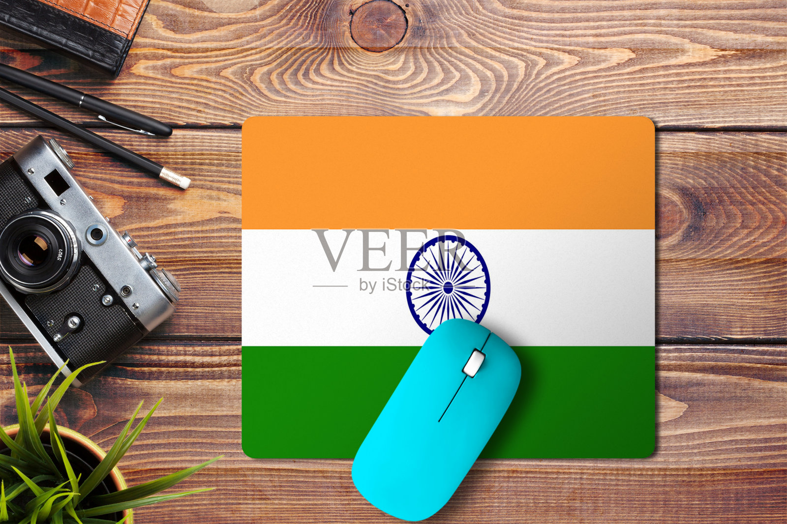 木质背景上印着印度国旗，鼠标垫上有蓝色无线鼠标，俯视图。数字媒体的概念。照片摄影图片